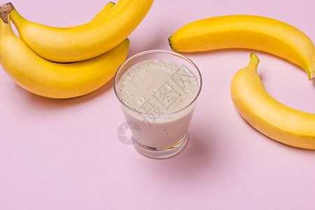 在粉红背景的玻璃杯中 新鲜制成香蕉冰淇淋早餐杏仁酸奶牛奶玻璃饮食奶油状食物黄色小吃图片