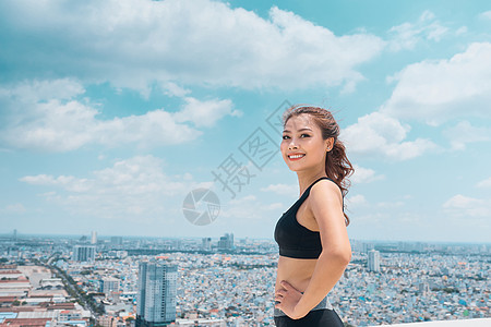 穿着运动服的年轻女子在蓝天上站在屋顶上微笑女士自由成人白色运动装女性头发运动员女孩身体图片