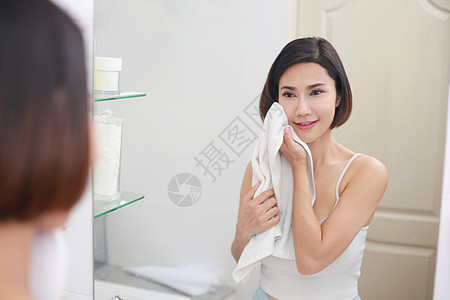 年轻的亚洲女人在洗手间用毛巾擦脸护理身体奶油女孩皮肤润肤浴室淋浴清洁度女士图片