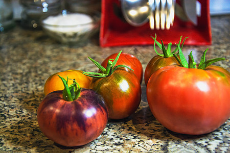 红番茄和绿色尾巴躺在大理石厨房的顶楼上图片