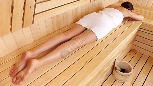 女人在木制桑拿室内休息 躺在她肚子的长椅上 身上裹着毛巾福利保健女士乐趣木头治疗呵护闲暇皮肤洗澡图片