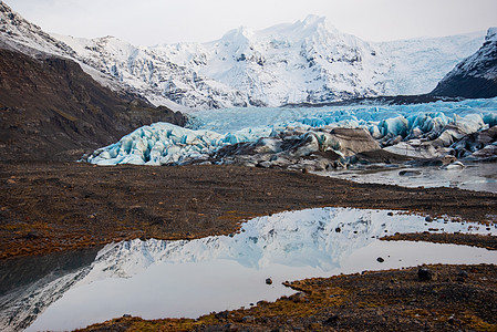 明亮的蓝色冰岛冰川 有冰河层 火山灰 雪和融化的水图片