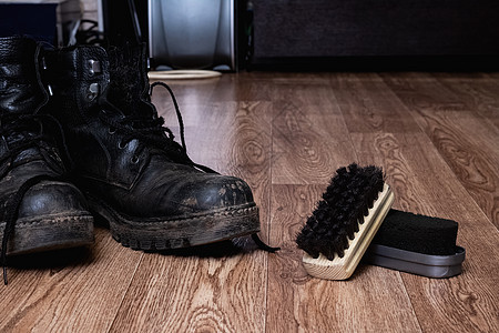 黑脏男人的鞋和木地板清洁用的刷子图片