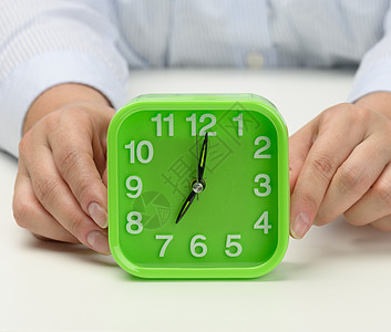 女人的手握着绿方闹钟 早上7点时钟显示 早起吧 开始吧女性数字绿色手表工作小时手臂警报唤醒戒指图片