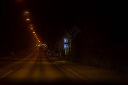 地下隧道 长长铺设道路 有暗的暖热照明和SOS路标图片