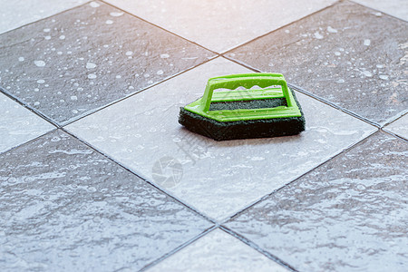 特写一个绿色的塑料刷子 用于洗涤和清洁放在湿瓦式地板上的地板图片