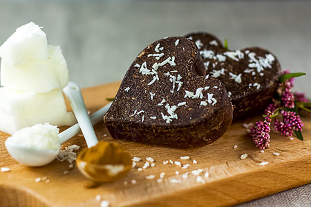 桌子上有由椰子油 椰子薯片和可可制成的手工巧克力 甜点根据适当营养的食谱制成艺术香气装饰盘子心形产品美食糖果木头棕色图片