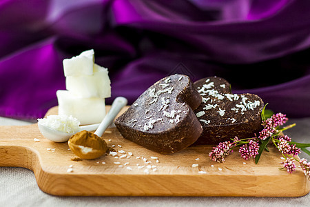 桌子上有由椰子油 椰子薯片和可可制成的手工巧克力 甜点根据适当营养的食谱制成艺术盘子棕色糖果香气风格烹饪产品木头心形图片