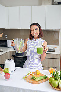 美丽的亚洲女人从厨房的搅拌机里倒冰淇淋重量蔬菜女性食物早餐微笑沙拉饮食水果女士图片