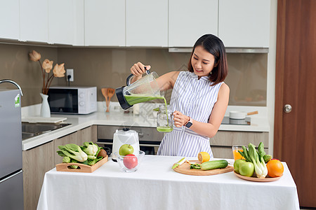 美丽的亚洲女人从厨房的搅拌机里倒冰淇淋水果微笑沙拉排毒饮食早餐女士蔬菜女性食物图片