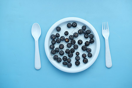蓝色背景的盘子上的新鲜蓝莓图片