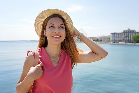 西班牙女孩美丽的微笑着的女士的肖像 仰望着城市里海边的一面背景