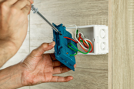 从木制墙上的插座上取出电源电插座 用螺丝起子检查电压图片