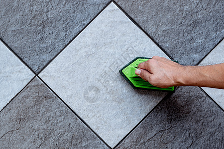 人手的顶部视线正在使用绿色塑料地板洗涤器 用地板清洁剂清洗瓷地板图片