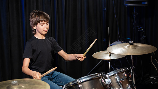 一个男孩在录音室里打鼓学习音乐家笔记记录鸡腿乐趣演员孩子们乐器教育图片
