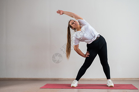 年轻胖女人在白色背景上做灵活练习的年青胖妇女肌肉灵活性身体闲暇瑜伽微笑动机数字体育锻炼女士图片