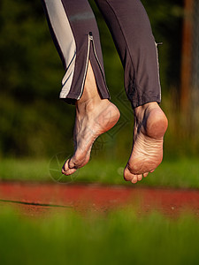 中年妇女伸膝和脚踝 赤脚跳跃女人运动员绑腿工人体育场训练定期培训赤脚跑步时间图片