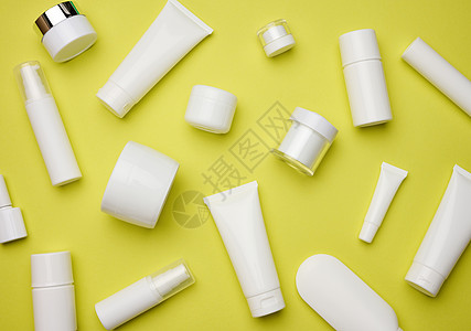 黄背景化妆品的罐 瓶和空白塑料管 用于奶油 凝胶 血清 广告和产品促销的包装 顶视图片