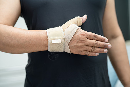 亚洲中年妇女用弹性绷带亲手和手指在办公室治疗德克韦因综合症 20手腕笔记本症状商业肌肉肿胀治愈愈合人士疾病图片