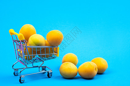 蓝色背景的有杏子的购物篮 购物车店铺商品销售甜点杂货店商业贸易产品小吃零售图片