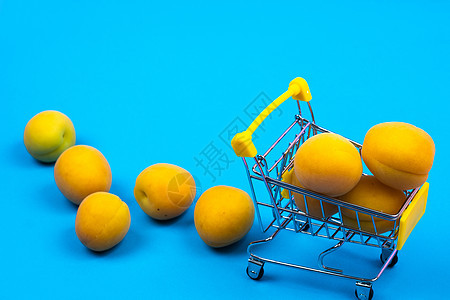 蓝色背景的有杏子的购物篮 购物车零售杂货店甜点食物贸易水果销售商品消费者店铺图片