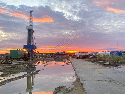 一油田 有石油钻机和货车 日落时在水坑中反射下巴工地平台天空场地活力建筑萃取生态工具图片