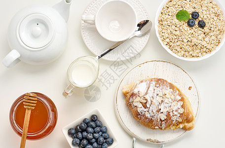 白陶瓷板 蓝莓 白桌上蜂蜜 早餐中的燕麦桌子牛奶粮食稀饭薄片烹饪食物谷物餐巾种子图片