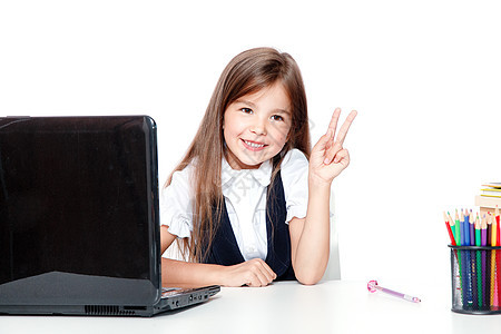 坐在笔记本电脑上的快乐和可爱的青少年女学生桌子瞳孔老师教育阅读微笑学校互联网考试班级图片