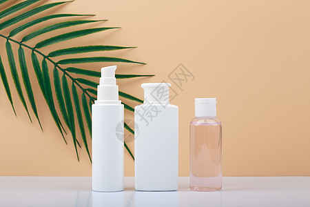 白桌上的化妆瓶排成一排 用棕榈叶与明亮的蜜蜂背景相对图片