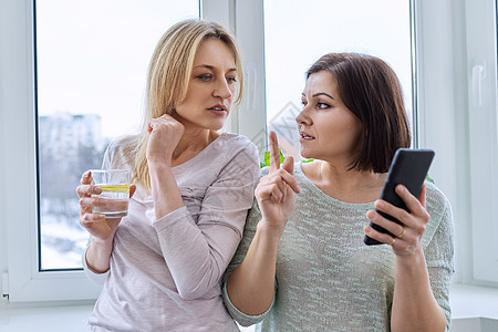 两位中年女性朋友一起看智能手机屏幕 在网上观看乐趣互联网成人电话阅读闲暇窗户朋友们技术友谊图片