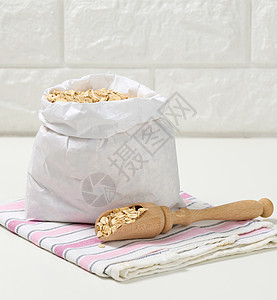 白纸袋中的粗燕麦片和白桌上的木勺子 早餐粥食物桌子稀饭燕麦粮食麦片谷物种子饮食营养图片