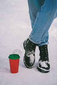 纸杯在雪上站立 在靴子的脚边图片