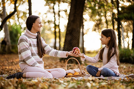 公园中的家庭日光橙子乐趣食物篮子头发野餐孩子女士叶子图片
