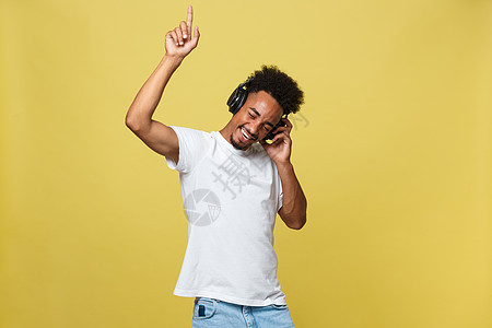 非裔非洲青年男子戴耳机 在黄色金色背景上享受音乐与黄金背景相比男人男性爆炸工作室白色国家成人歌曲闲暇头发图片