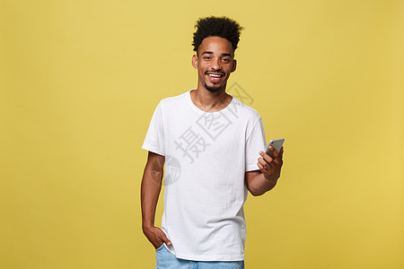带着微笑和手机的非洲快乐男子 在黄色背景上孤立无援 笑声商业技术电话细胞人士白色消息黑色男性成人图片