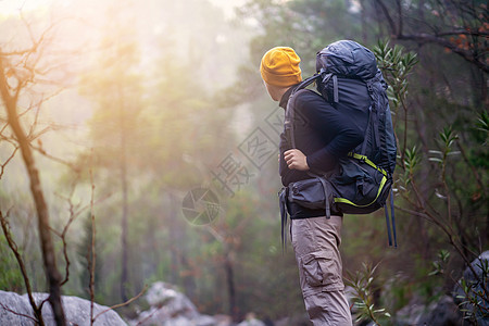 一个年轻旅行者背着背包 爬上山去图片