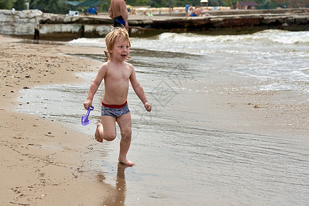 一个小男孩沿着海滨沙沙滩跑来跑去海岸乐趣旅行孩子家庭童年海洋喜悦太阳假期图片