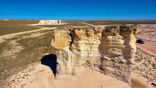 白色大柱状岩石 在平坦的沙漠中 用汽车透视图片