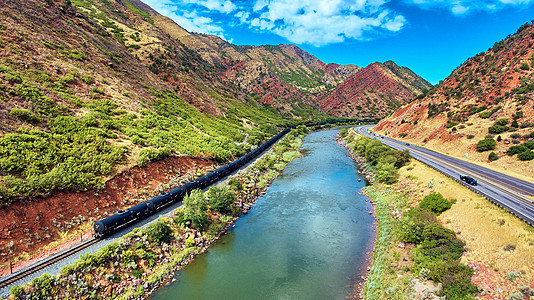 穿越红岩山和河流谷地的铁路上火车图片