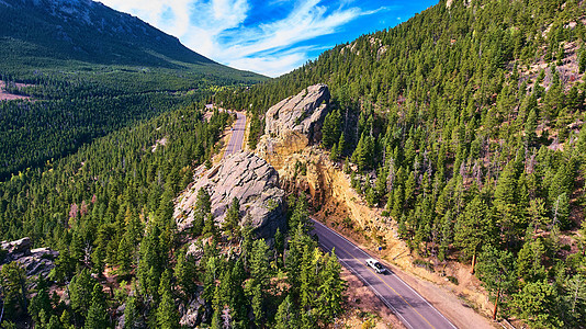 穿过松树山中的大巨石的公路图片