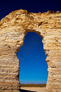 以大胆蓝色天空梯度横穿天然石墙的拱门图片