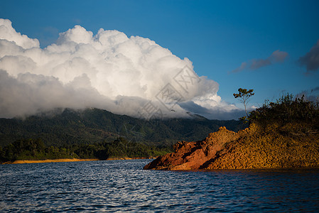 坐在小岛后面的一艘船上 满是乌云假期山脉风景戏剧性树木旅行环境天空蓝色反射图片