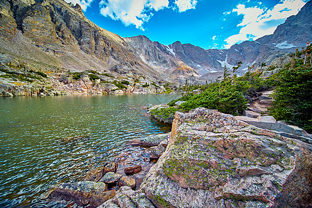 在山环绕的湖中休息的大块巨石上的绿利钦图片