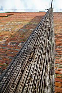 在红砖楼上运行的粗制木质木质电线杆图片