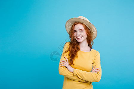 旅行概念     特写肖像 年轻漂亮的有吸引力的红头发女孩Wtih时尚帽子和墨镜笑脸 蓝面纸背景魅力乐趣女性太阳海滩太阳镜潮人假图片