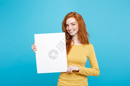 近距离接近肖像的年轻美丽有吸引力的姜红发女孩 微笑着显示空白标志 蓝糊背景 复制空间广告卡片广告牌床单商业学生木板人士工作室女士图片