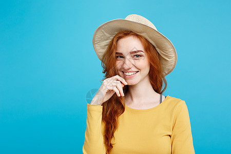 旅行概念 - 用时髦的帽子和笑容把肖像年轻漂亮的红头发女孩关上 蓝面画背景 复制空间图片