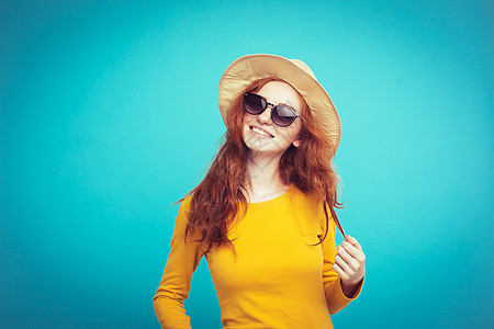 旅行概念     特写肖像 年轻漂亮的有吸引力的红头发女孩Wtih时尚帽子和墨镜笑脸 蓝面纸背景裙子假期潮人微笑女性太阳魅力乐趣图片