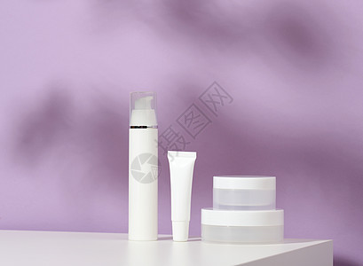 用于紫底化妆品的罐头和空白塑料管 奶油 凝胶 血清 广告和产品促销的包装 模拟清洁剂卫生紫色品牌桌子皮肤润肤小样洗发水护理背景图片