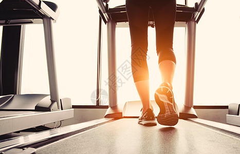 健身女孩腿部的下半身在跑步机或跑步机上跑步 在带有阳光的健身健身房 暖色调 健康和锻炼活动的概念 锻炼和力量训练主题女士运动员女图片